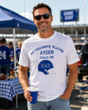 Dad at a football tailgate wearing a white personalized Football Dad shirt with AYDEN embroidered in blue and a blue helmet appliqué.